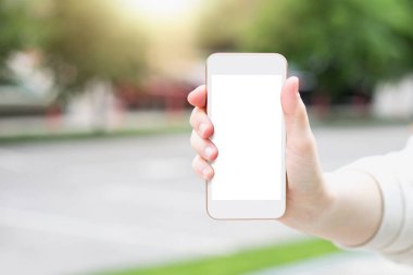 Beyaz ekranlı telefon modeli. kopyalama alanı. Kadın eli, arka planda boş ekranı olan beyaz bir akıllı telefonu şehrin arka sokaklarında tutuyor. Boş telefon ekranı gösteren bir kadın. Modelleme. Tasarım için yer