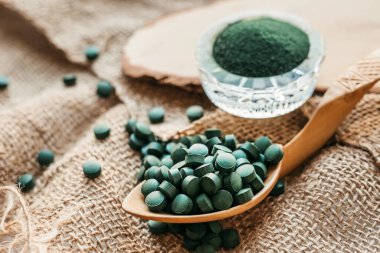 Tabletlerde yeşil yosun spirulinası ve çuval bezinde pudra. Sebze proteini