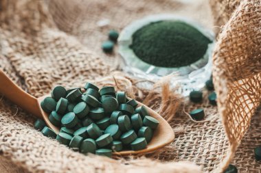 Tahta kaşık ve spirulina tabletleri, çuval bezinde klorella tozu. Detoks süper yiyecekler