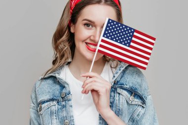 Kırmızı rujlu kız çocuğu küçük bir Amerikan bayrağı tutuyor ve turuncu arka planda saklı gülümsüyor, elinde ABD bayrağı tutan kadın, 4 Temmuz Bağımsızlık Günü, kopyalama alanı
