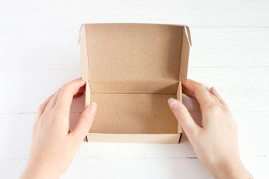 Kadın elleri beyaz ahşap arka planda boş bir kravat kutusunu tutuyor.