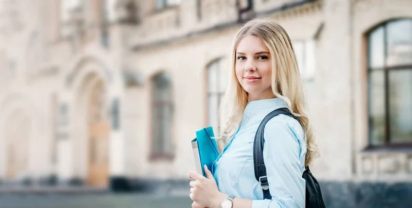 Блондинка Студентка Посміхається Тримає Папку Блокнот Своїх Руках Університетському Тлі — стокове фото