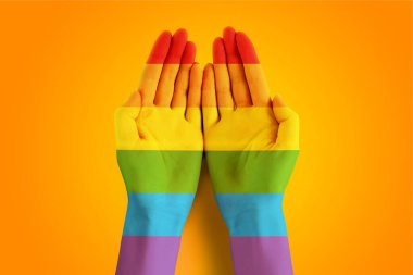 Turuncu ve sarı arka planda LGBT bayrak rengine boyanmış kadın elleri. LGBT tolerans geçmişi, gurur günü konsepti. LGBT toplum hakları ve özgürlük kavramı, kopyalama alanı