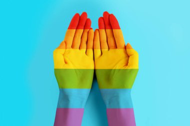 Mavi arka planda LGBT bayrak rengine boyanmış kadın elleri. LGBT tolerans geçmişi, gurur günü konsepti