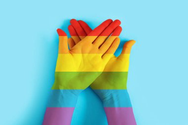 Mavi arka planda LGBT bayrak rengine boyanmış kadın elleri. LGBT tolerans geçmişi, gurur günü konsepti