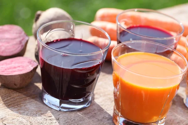 Karotten- und Rote-Beete-Saft auf dem Gartentisch. — Stockfoto