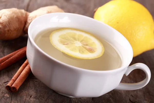 Close up of cup with ginger tea and ingredients. — Stock Photo, Image