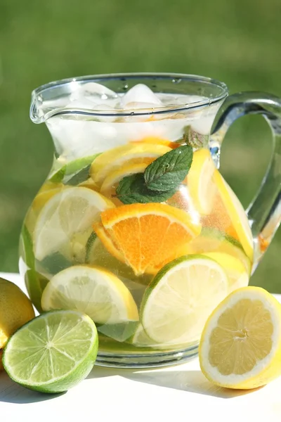 Jug with fresh fruit lemonade in a garden — Stock Photo, Image