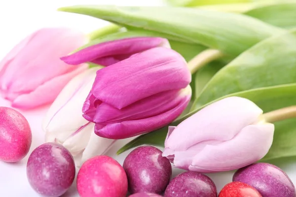 Primo piano di uova di caramella e tulipani — Foto Stock