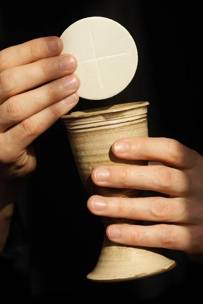 Händer med kalk och nattvarden (wafers) — Stockfoto