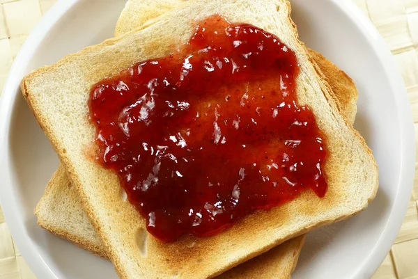 Toast met aardbeienjam op plaat. — Stockfoto