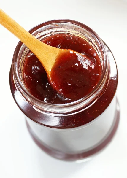 Glass with strawberry jam and spoon — Stock Photo, Image