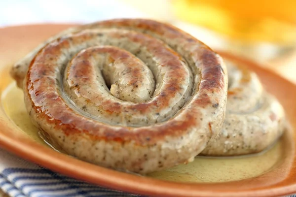 Embutidos en espiral sobre plato con vaso de cerveza —  Fotos de Stock