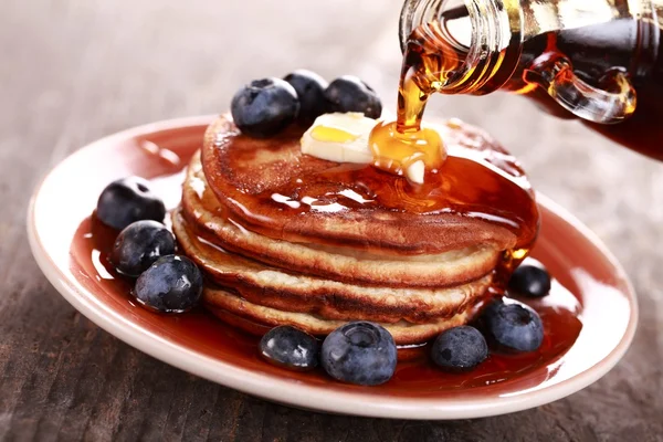 Pouring maple syrup on stack of pancakes — Stock Photo, Image