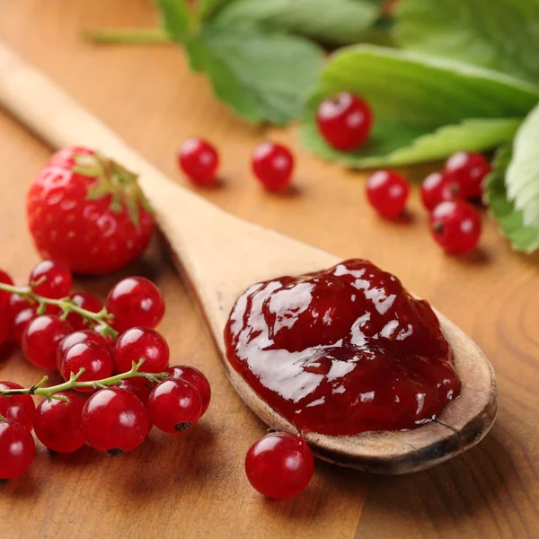 Close-up of wooden spoon with jam and berry fruits. — Stock Photo, Image