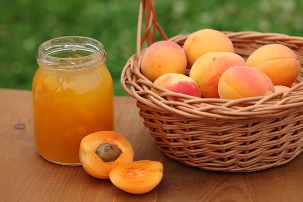 Vetro con marmellata di albicocche e albicocche fresche nel cestino — Foto Stock