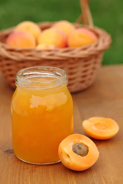 Glass with apricot jam and fresh apricots in basket — Stock Photo, Image