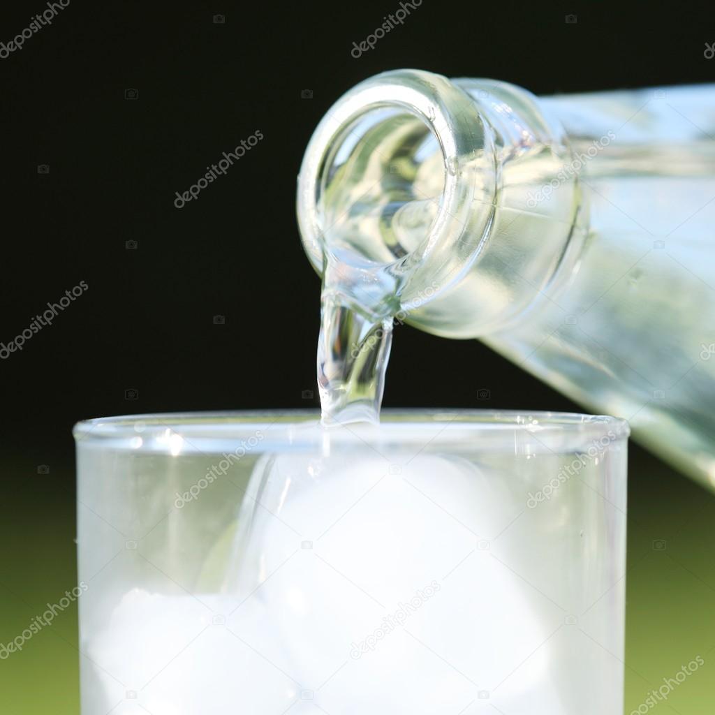 Close-up of glass bottle and pouring water into glass
