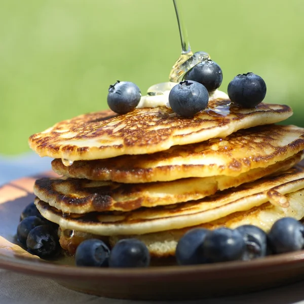 Pouring syrup on pancakes with blueberries. — Stock Photo, Image