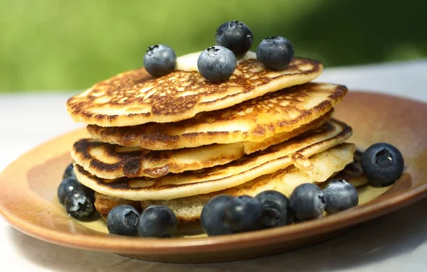 Stack of pancakes with blueberries on garden table — Stock Photo, Image