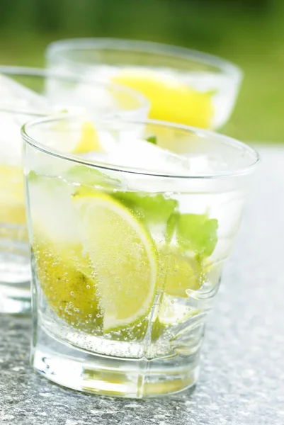 Fresh drink with ice cubes, lemon, lime and mint — Stock Photo, Image