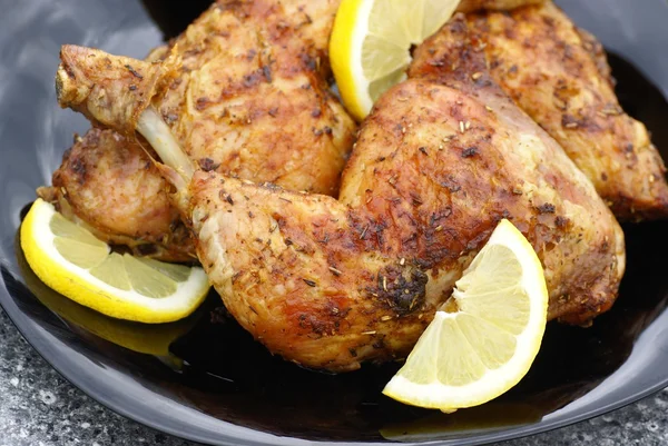 Мясо курицы на гриле с лимоном на черной тарелке — стоковое фото