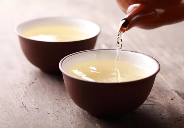 Close-up of tea pot ant tea pouring into bowl. — Stock Photo, Image