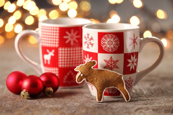 Mugs with hot drink and gingerbread cookie.