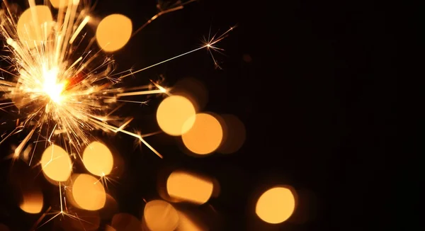 Close-up of sparkler on Christmas lights background — Stock Photo, Image