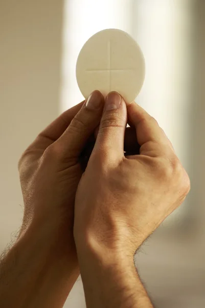 Hands holding communion wafer at church interior. — Stock Photo, Image