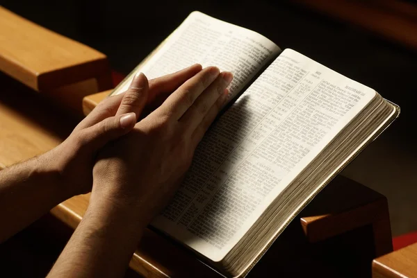 Manos sobre la Santa Biblia en oración en la iglesia —  Fotos de Stock