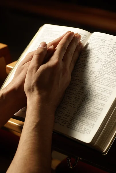 Hände an der Heiligen Bibel im Gebet in der Kirche — Stockfoto