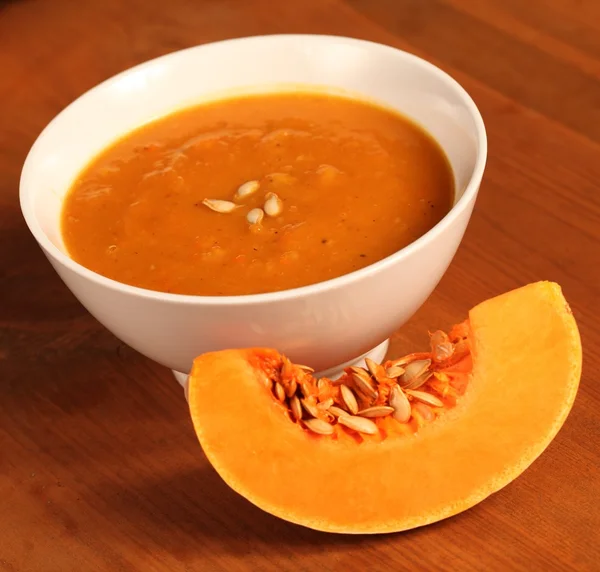 Schüssel mit Kürbissuppe und Scheibe frischem Kürbis — Stockfoto