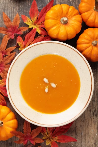 Piatto con zuppa di zucca e decorazioni autunnali . — Foto Stock