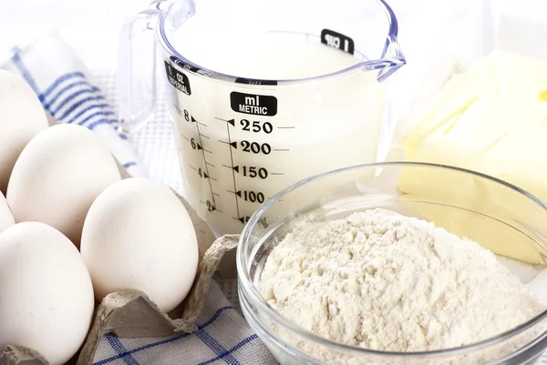 Detalj av ägg, mjölk, mjöl och smör på ett bord. — Stockfoto