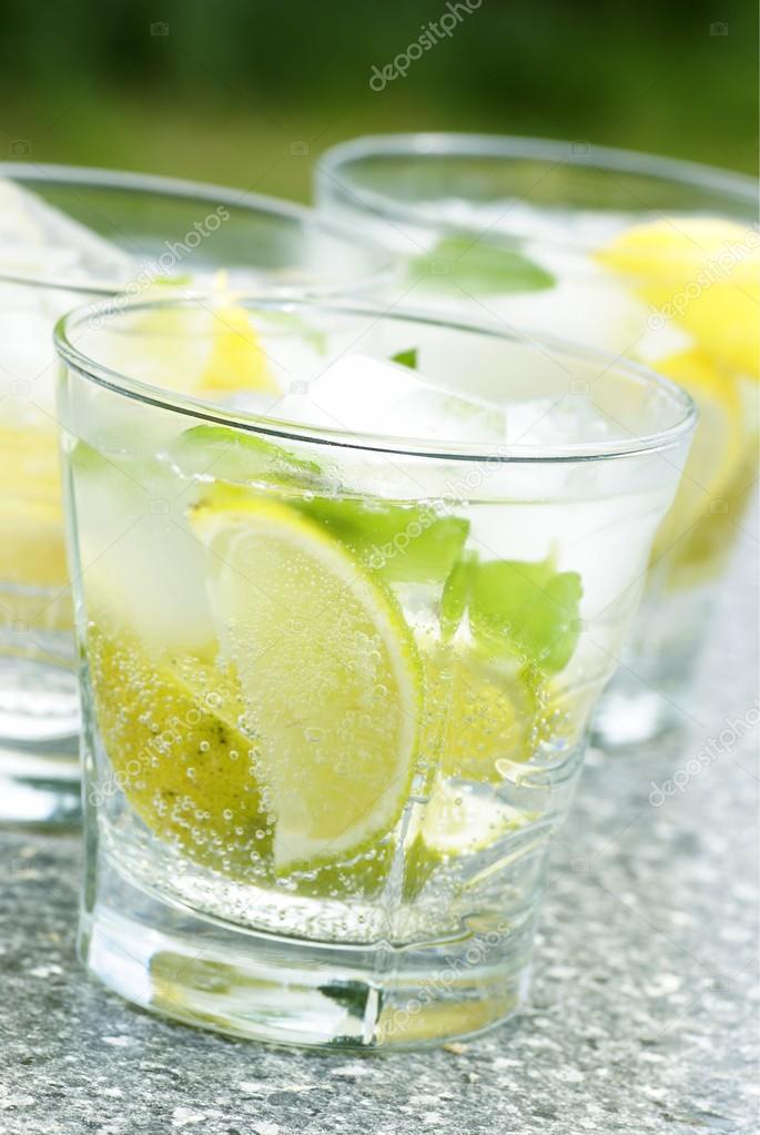 Fresh drink with ice cubes, lemon, lime and mint.