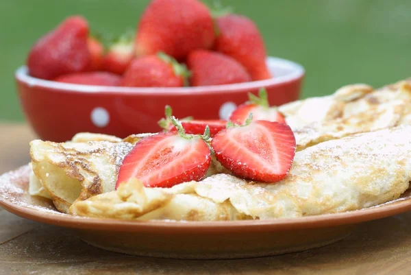 Söta crêpes med jordgubbar på trädgårdsbord. — Stockfoto