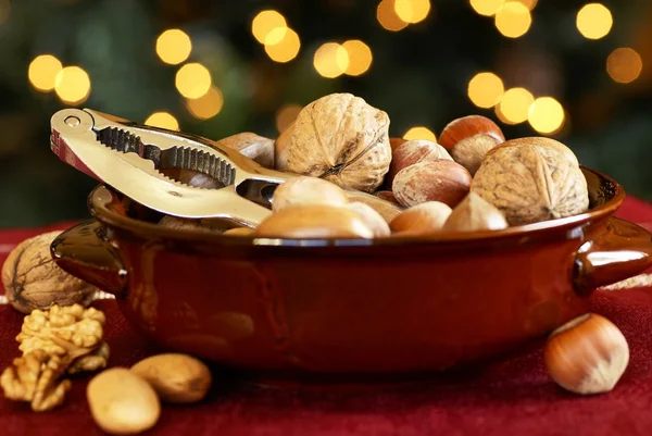 Nussknacker und Nüsse in einer Schüssel mit Weihnachtsbeleuchtung Hintergrund. — Stockfoto