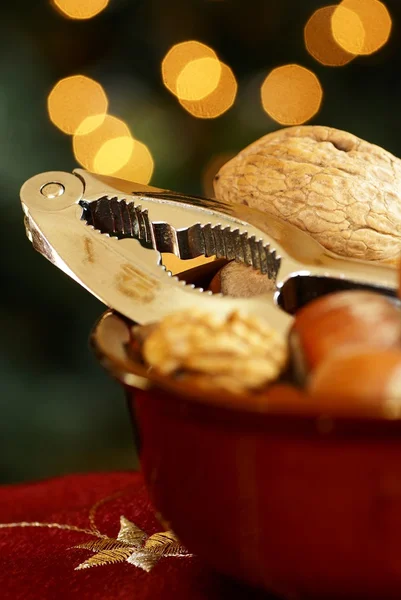 Nussknacker und Nüsse in einer Schüssel mit Weihnachtsbeleuchtung Hintergrund. — Stockfoto