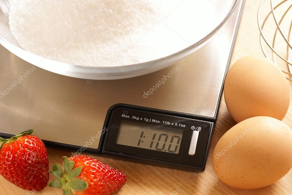 Kitchen scale with bowl with sugar and eggs