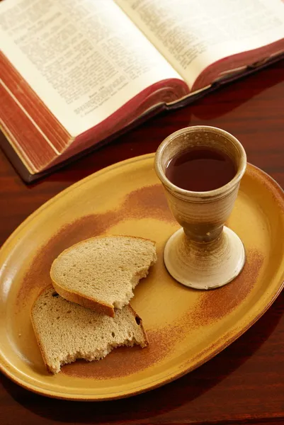 Kalich, chléb a otevřené Bibli na stůl. — Stock fotografie