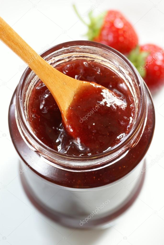 Glass with strawberry jam and spoon