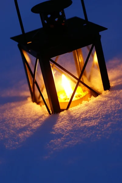 Latarnia z płonącą świecą na śniegu w godzinach wieczornych. — Zdjęcie stockowe