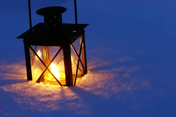 Lanterne avec bougie allumée sur neige le soir . — Photo