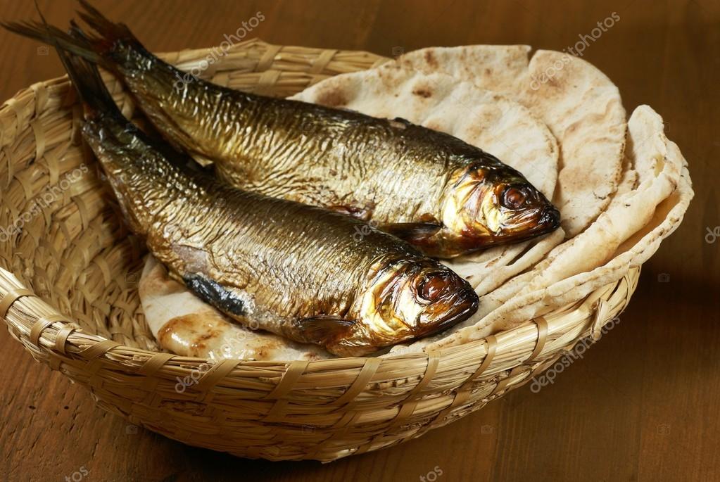 Loaves of bread and two fishes in a basket. Stock Photo by ©MKucova