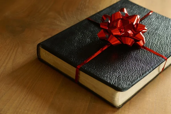 Bible with ribbon as a gift on wooden background. — Stock Photo, Image