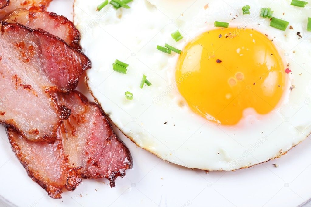 Close-up of fried egg and bacon on plate.