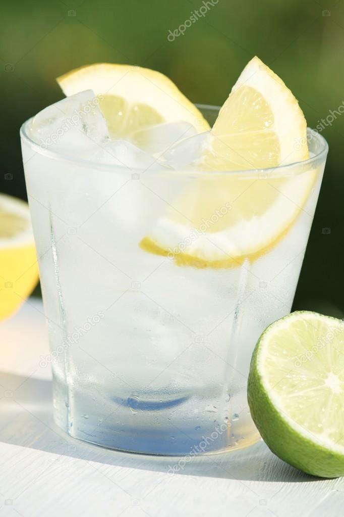 Fresh drink with ice cubes, lemon and lime