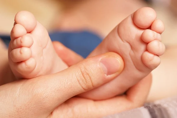 Madre sostiene los pies de su bebé — Foto de Stock