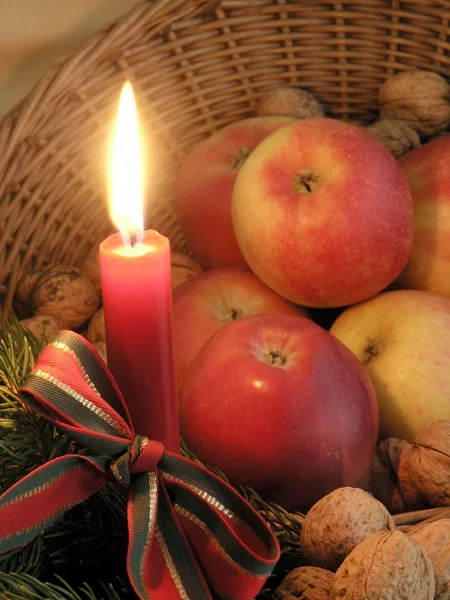 Candle, apples and walnuts in basket — Stock Photo, Image